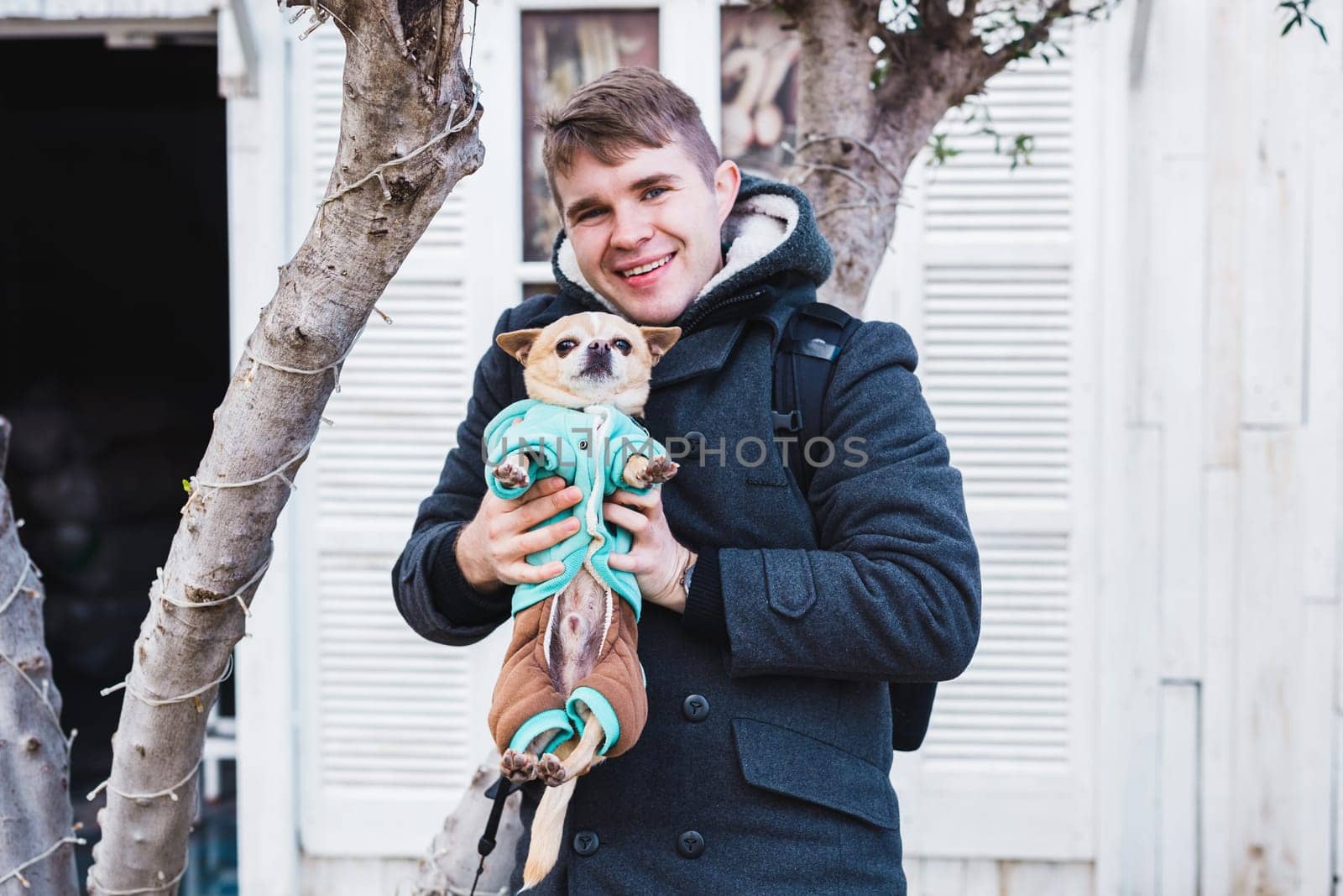 Closeup of handsome young man holding a cute chihuahua dog