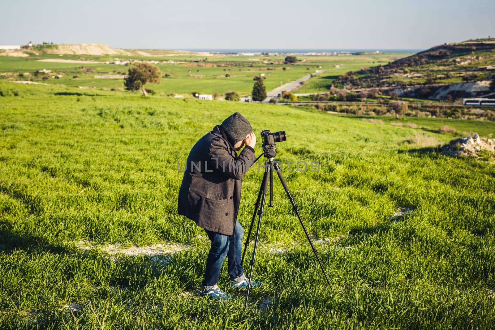 A photographer or traveller using a professional DSLR camera on a tripod in the nature for background