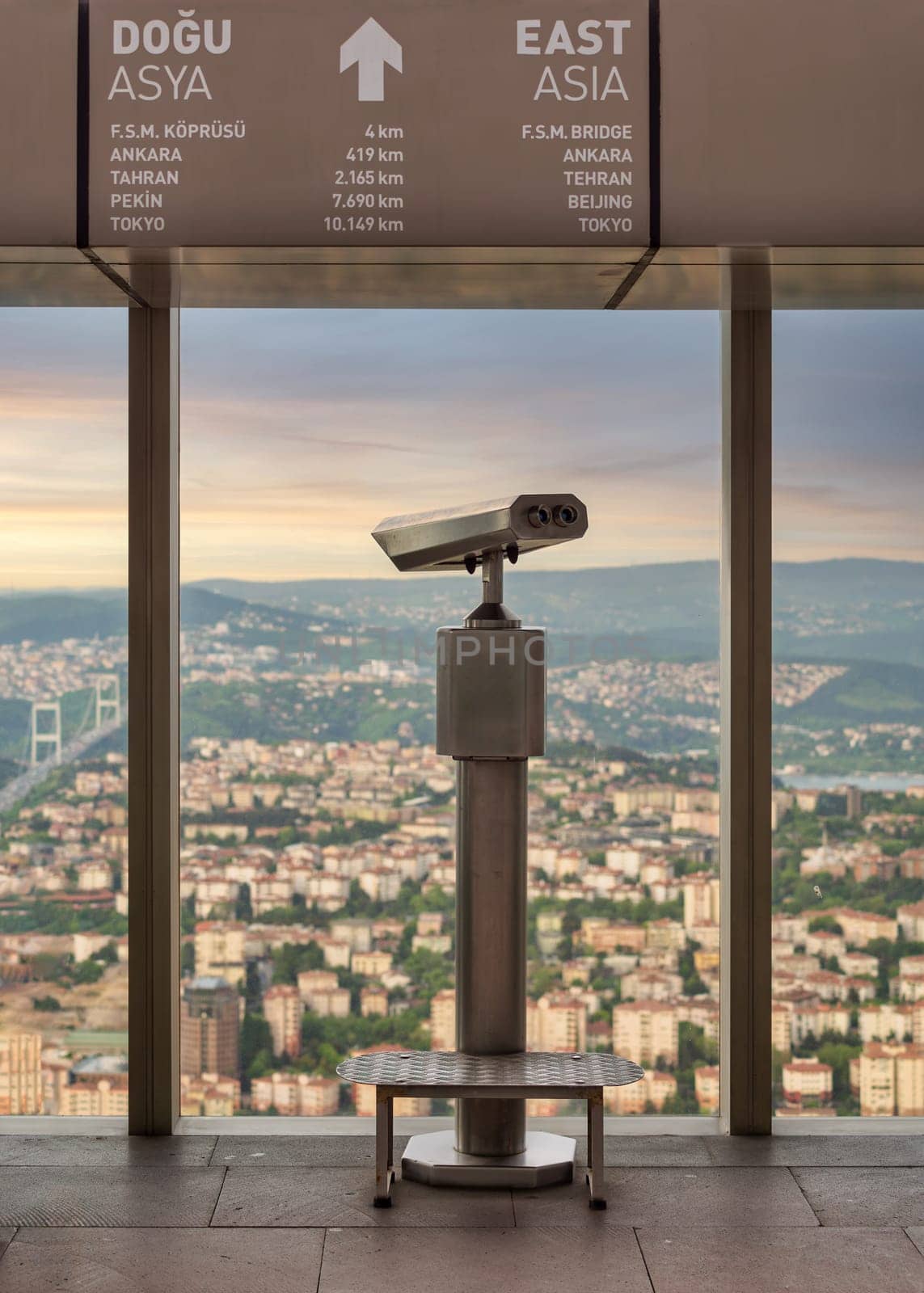 Tower Optical coin-operated binocular on the observation deck of Istanbul Sapphire,Turkey, against cityscape before sunset with sign including distances to some Asian capital cities to the east