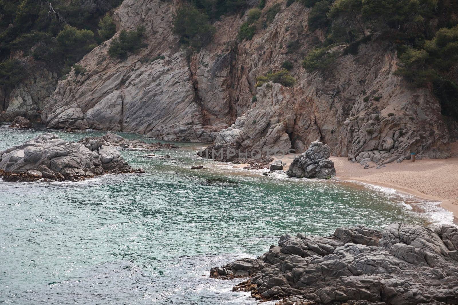 turquoise water of a sea bay near a steep rocky coast, deserted sandy beach, marine landscape