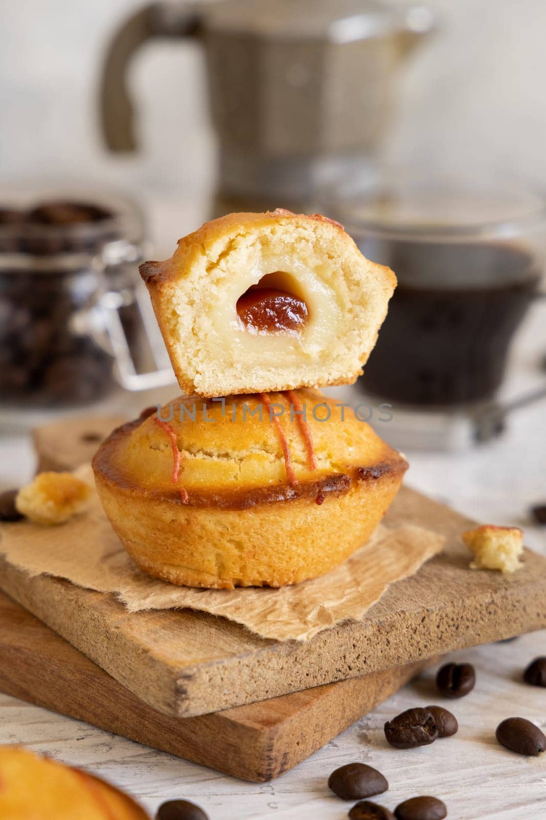 Pasticciotto leccese pastry filled with egg custard cream and sour cherry jam. Pieces of pasticiotto on a wooden board, typical apulian breakfast, close up. Table decorated with coffee beans