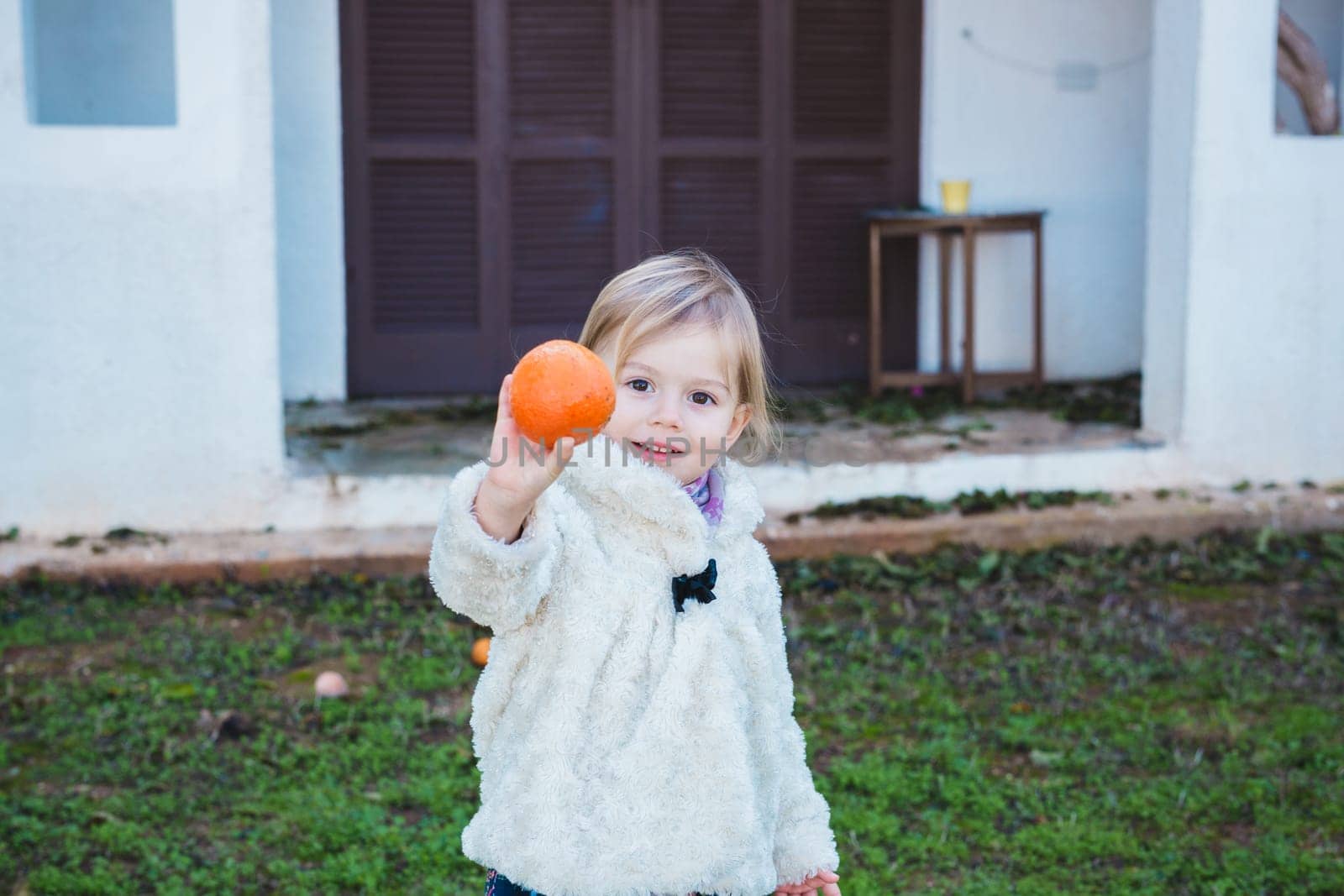Little girl holding apples in the garden