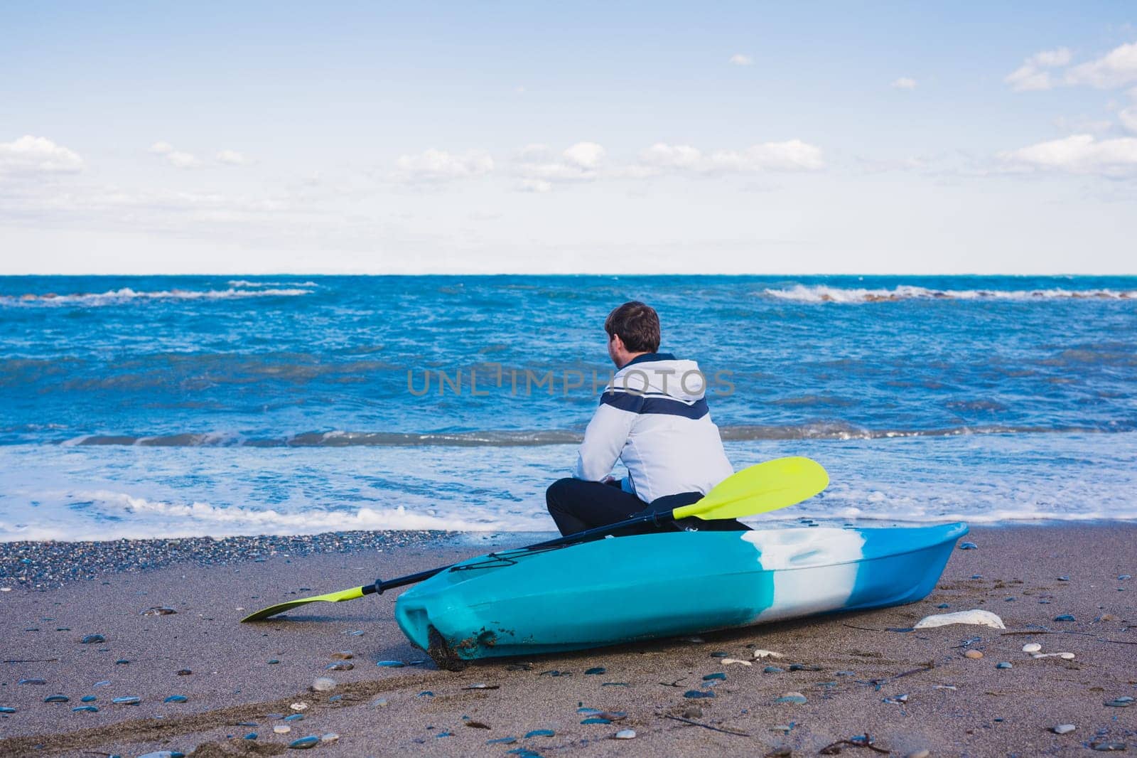 Man with kayak on the beach in sunny day.