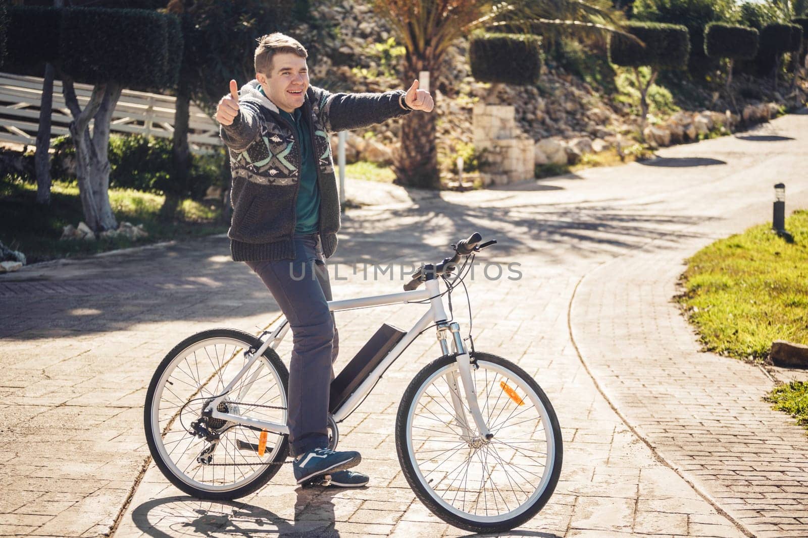 Young man riding bike in park showing thumb up.