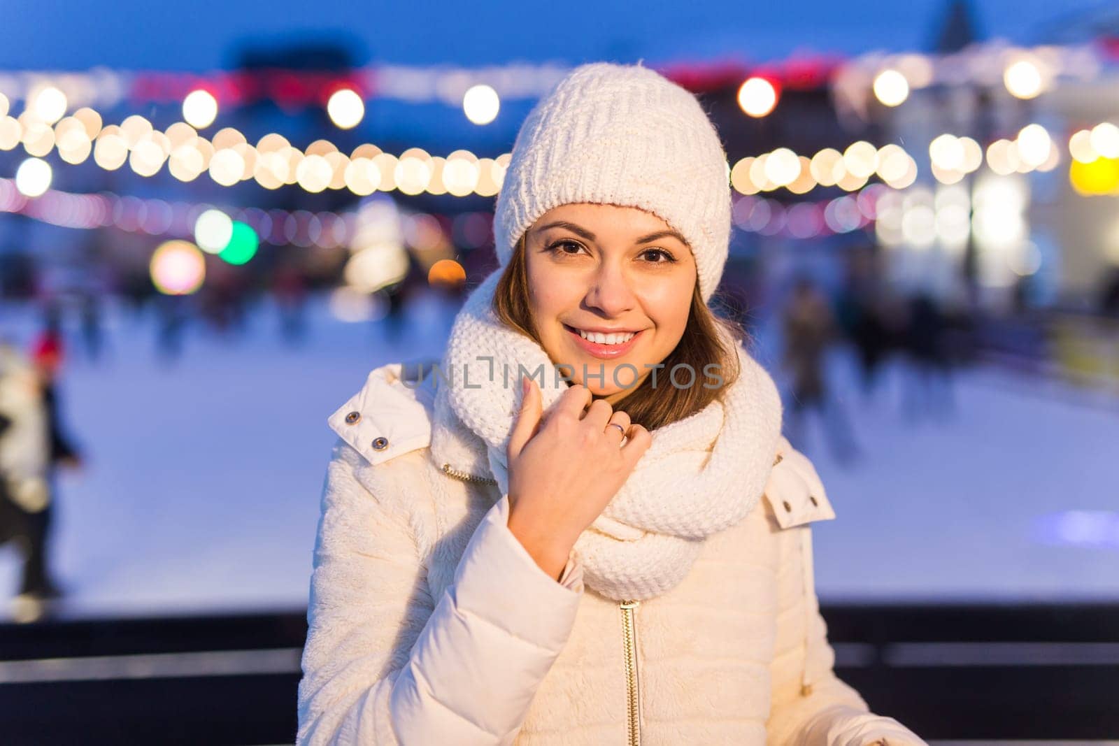Christmas, winter, technology and leisure concept - happy young woman taking picture with smartphone on ice skating rink.