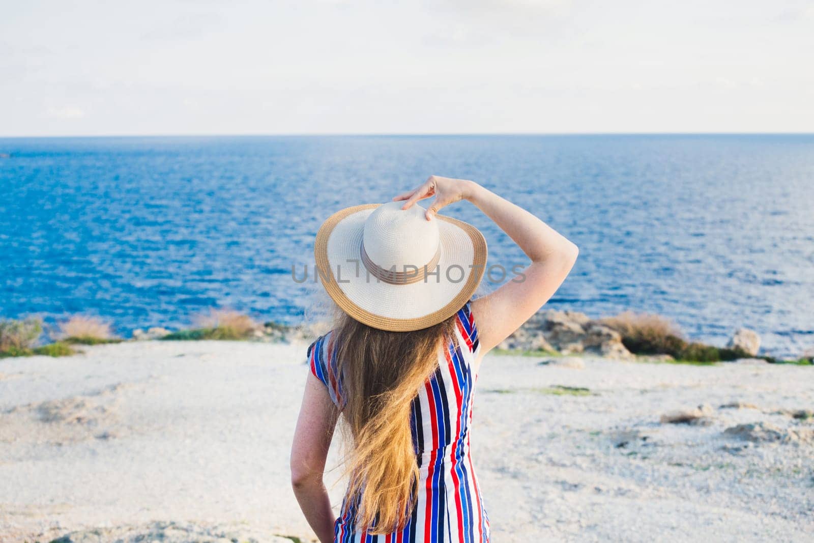 Happy woman enjoying beach relaxing joyful in summer by tropical blue water. Beautiful model happy on travel wearing beach sun hat.