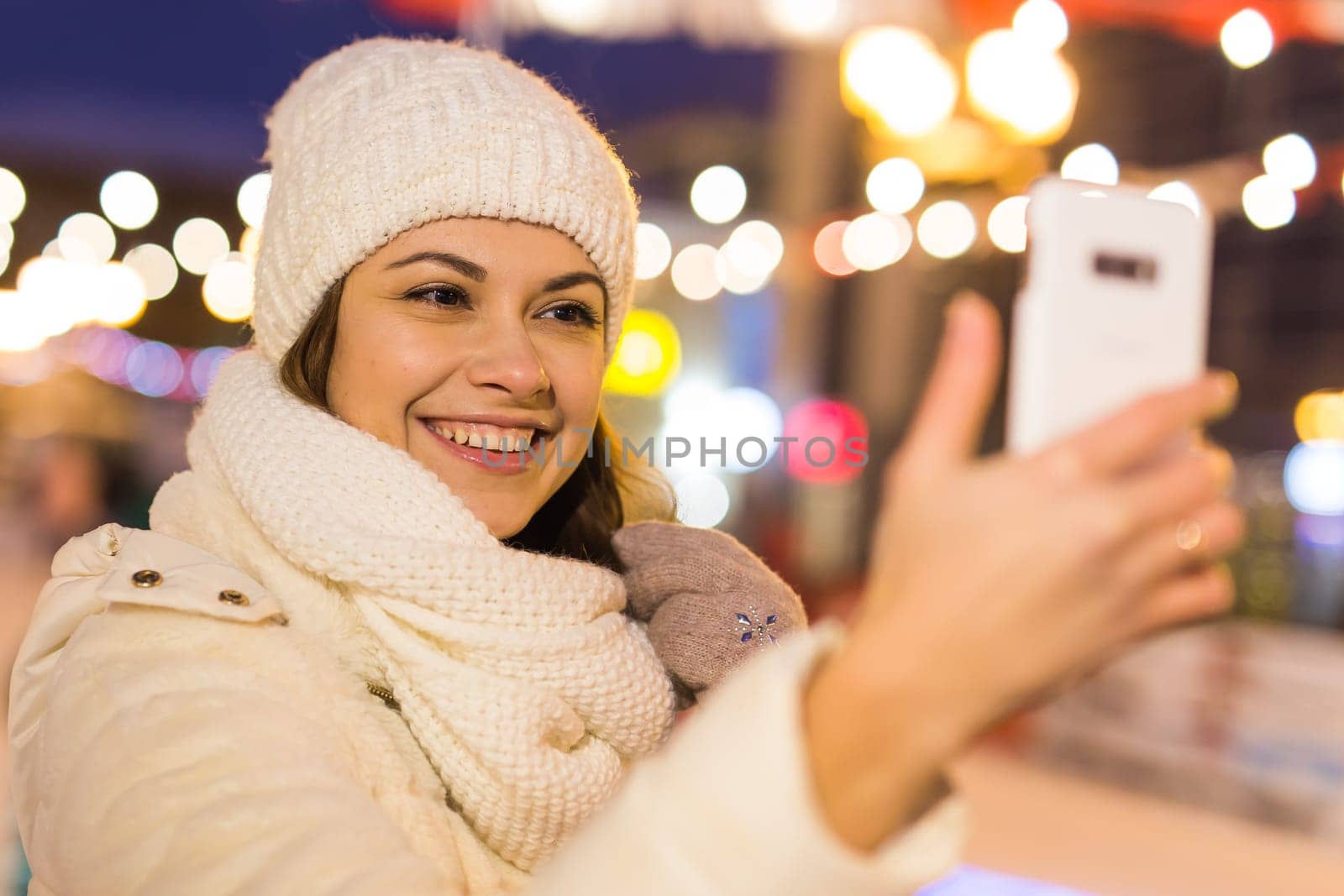 Happy young woman in winter on the ice rink taking picture on smartphone.