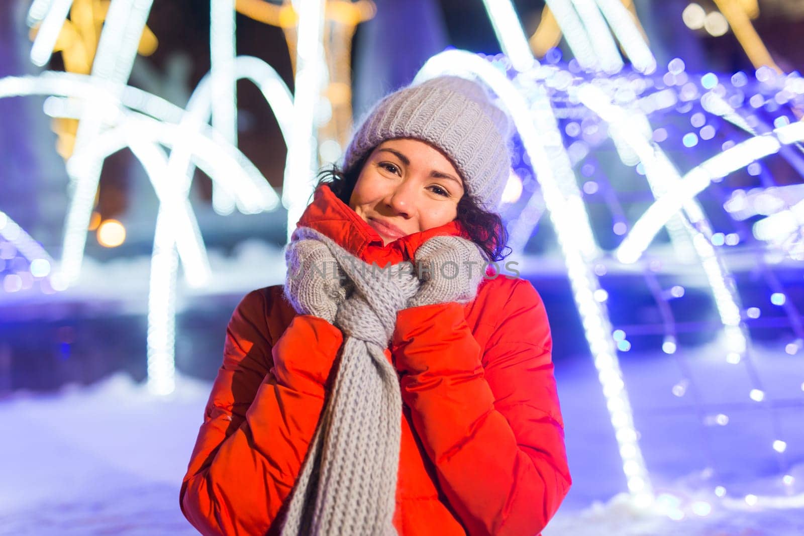 Winter holiday season. Christmas, New Year concept. Funny woman spend time having fun near illuminated and decorated showcase on city street.