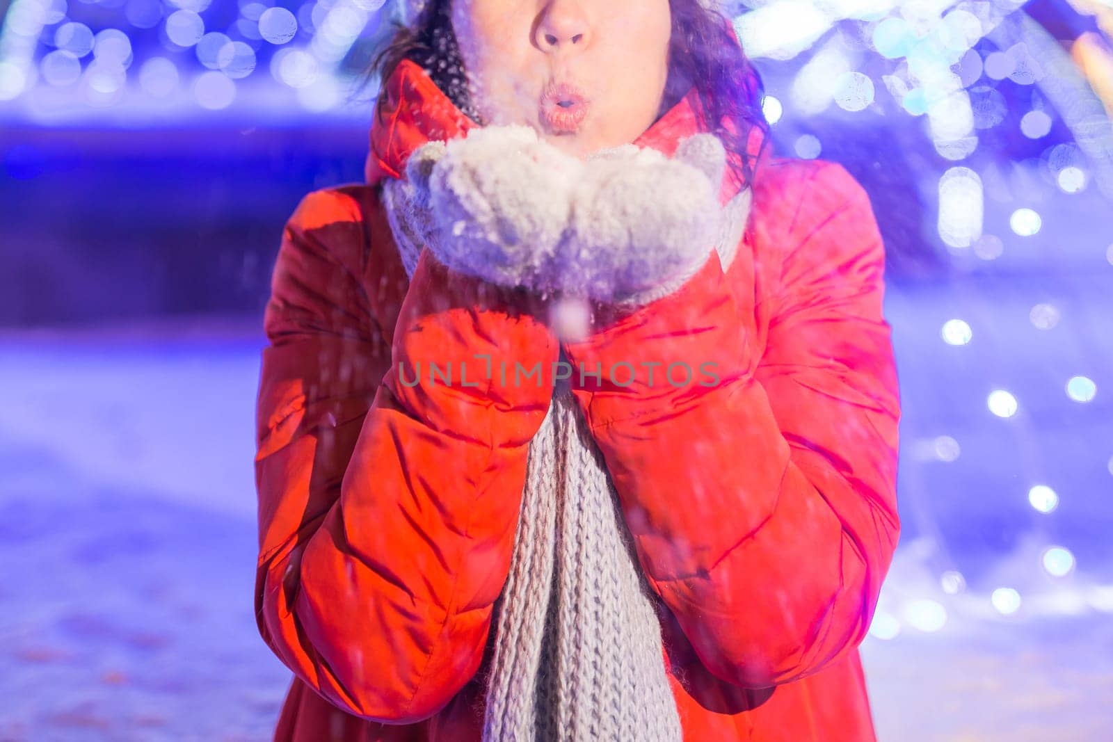 Girl having fun christmas decoration lights street. Young happy smiling woman wearing stylish knitted scarf and jacket outdoors. Model laughing. Winter wonderland city scene, New Year party.