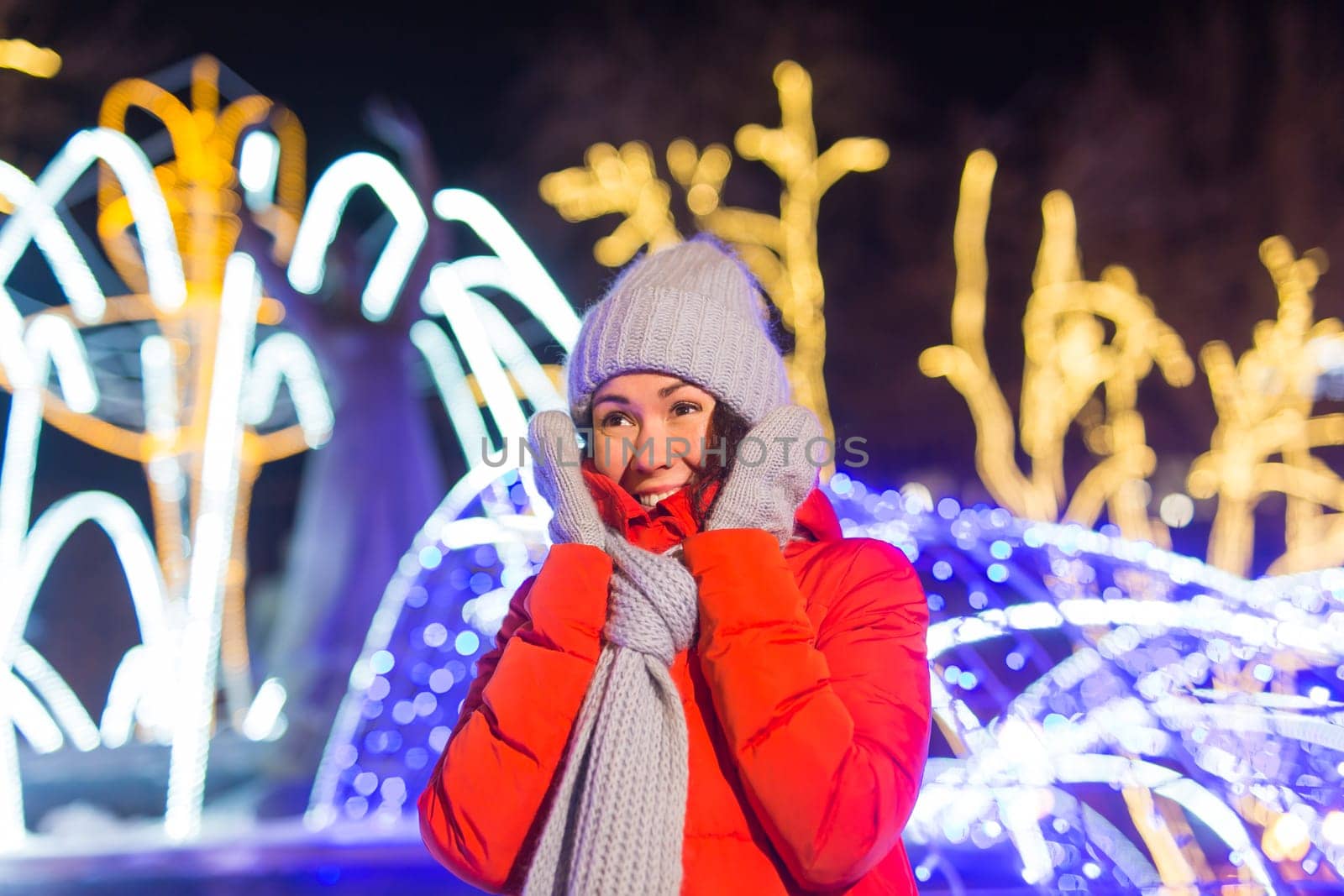 Winter holiday season. Christmas, New Year concept. Funny woman spend time having fun near illuminated and decorated showcase on city street.