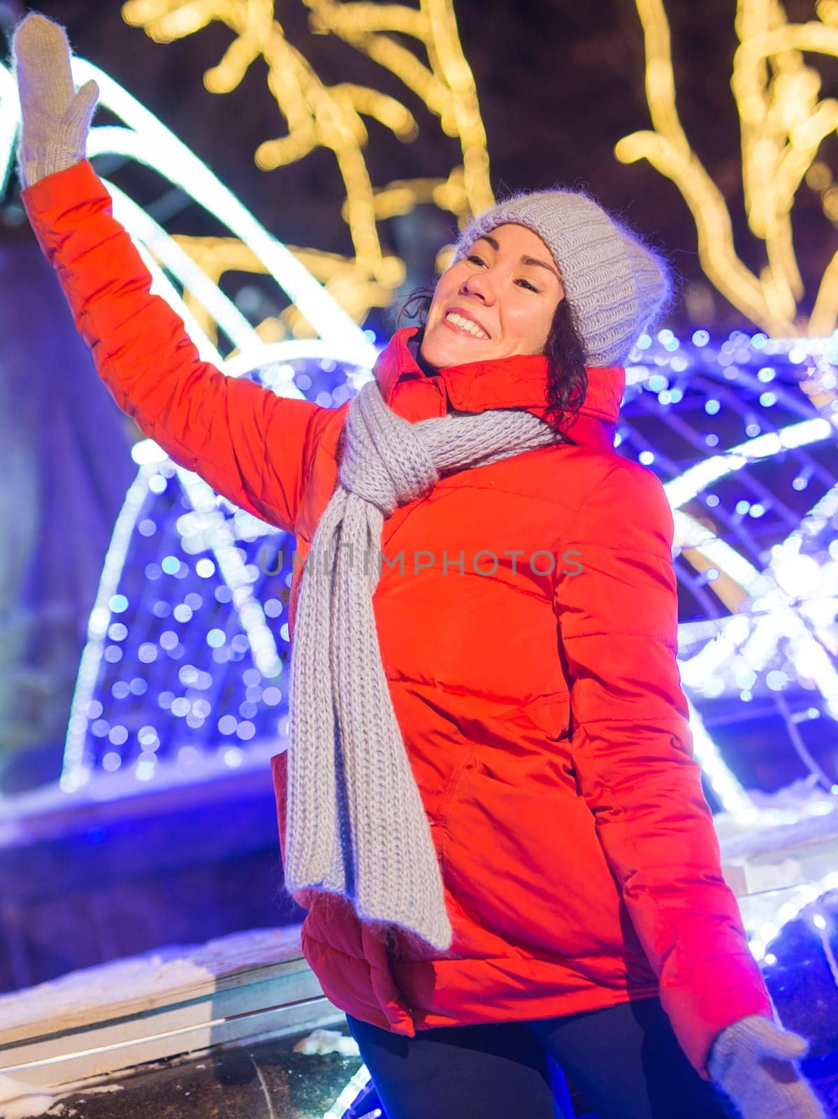 Winter holiday season. Christmas, New Year concept. Funny woman spend time having fun near illuminated and decorated showcase on city street.