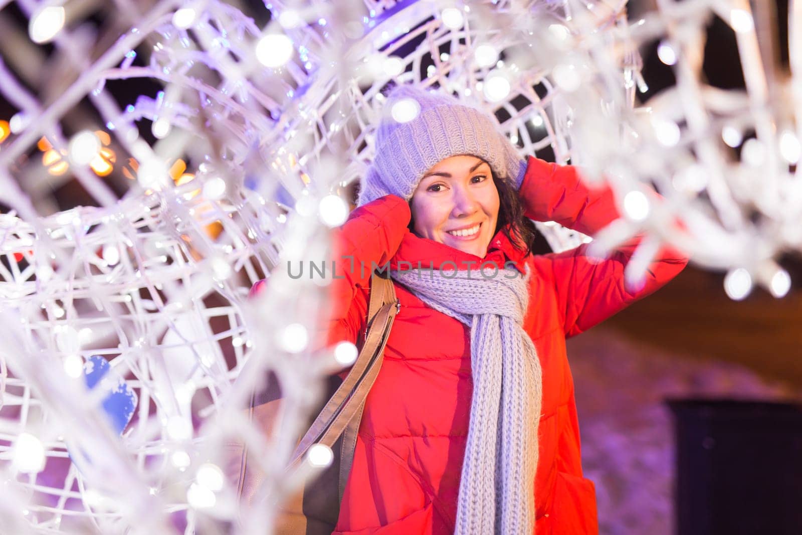 Winter holiday season. Christmas, New Year concept. Funny woman spend time having fun near illuminated and decorated showcase on city street.