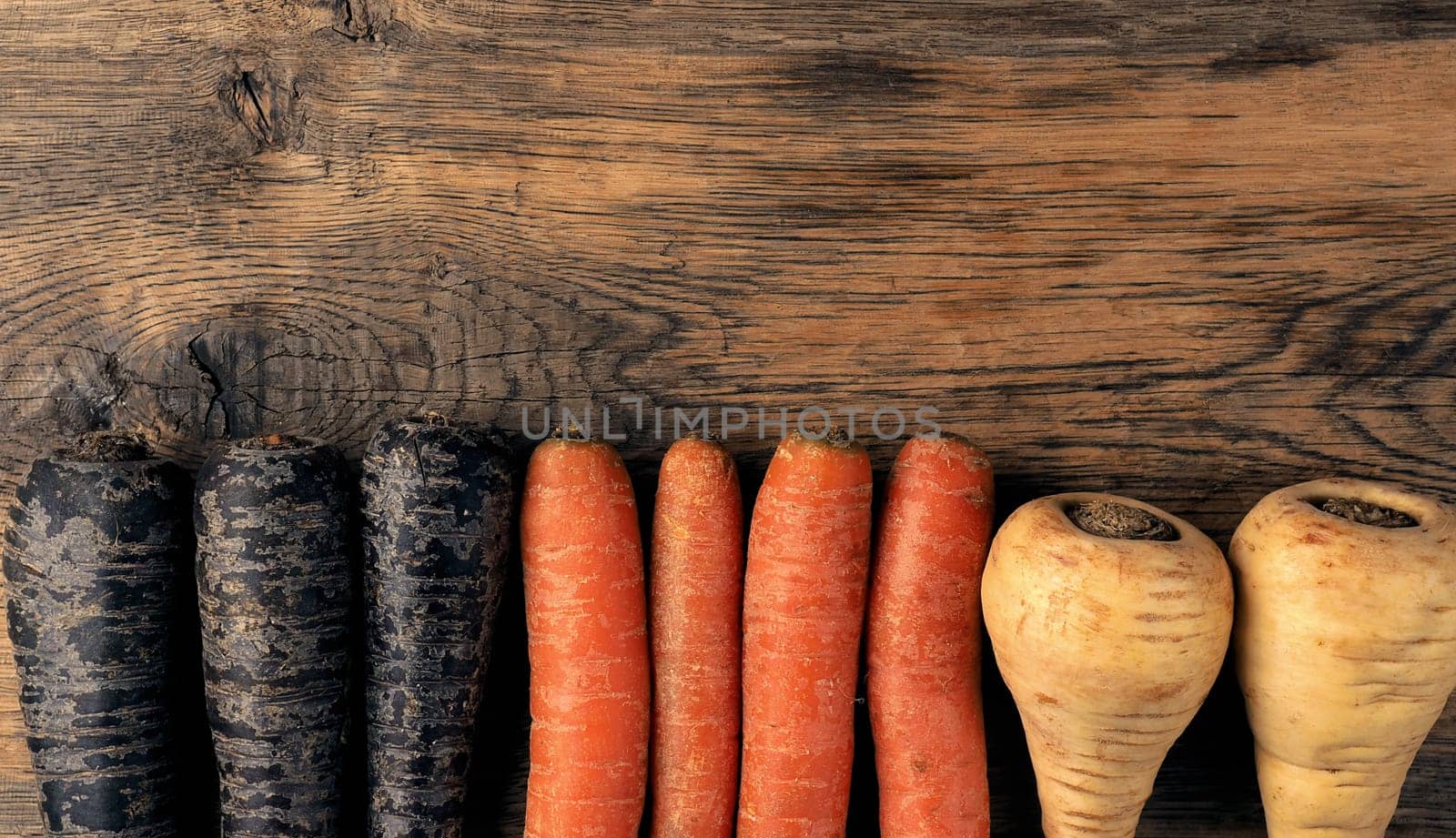 Three different root vegetables on a rustic wooden kitchen table on a dark background with space for text or image, healthy food or vegan ingredients concept, cover image, vegetarian food