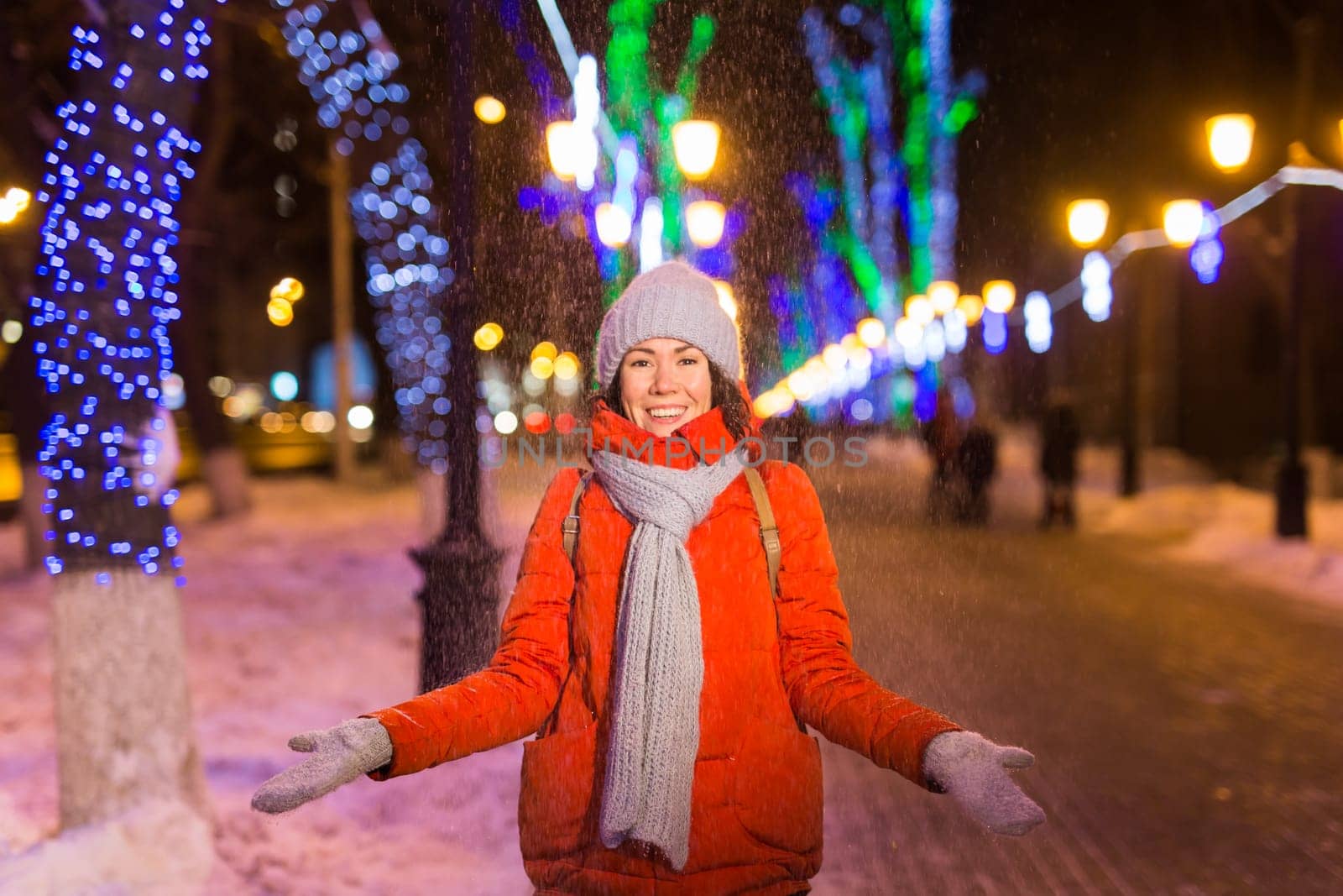 Winter holiday season. Christmas, New Year concept. Funny woman spend time having fun near illuminated and decorated showcase on city street.