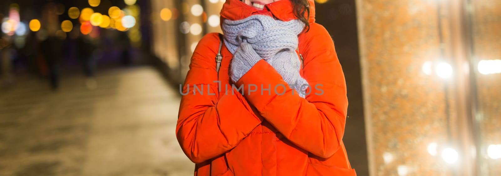 Happy funny young woman with winter clothes background evening city lights illumination. Christmas and winter holidays.