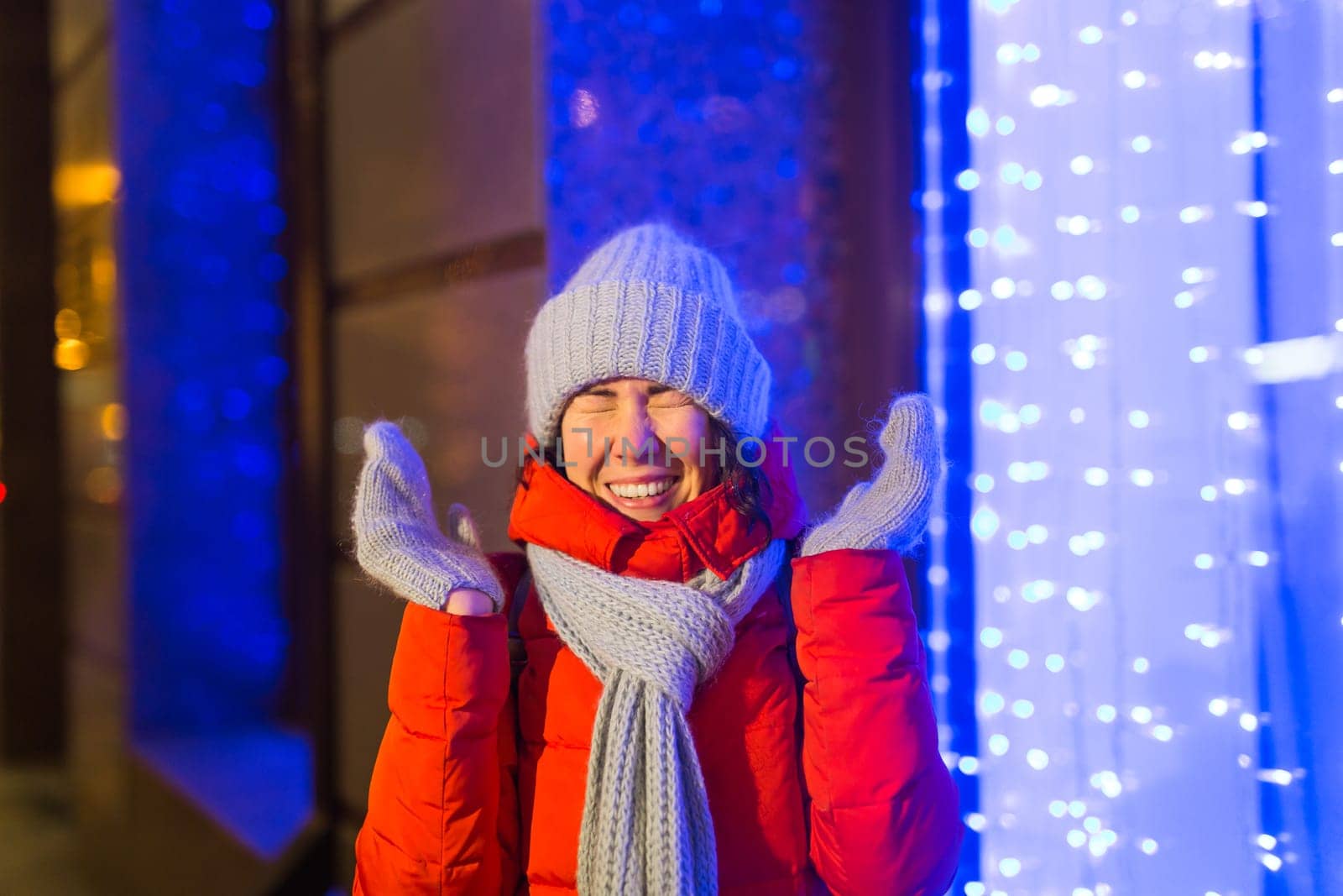 Winter holiday season. Christmas, New Year concept. Funny woman spend time having fun near illuminated and decorated showcase on city street.