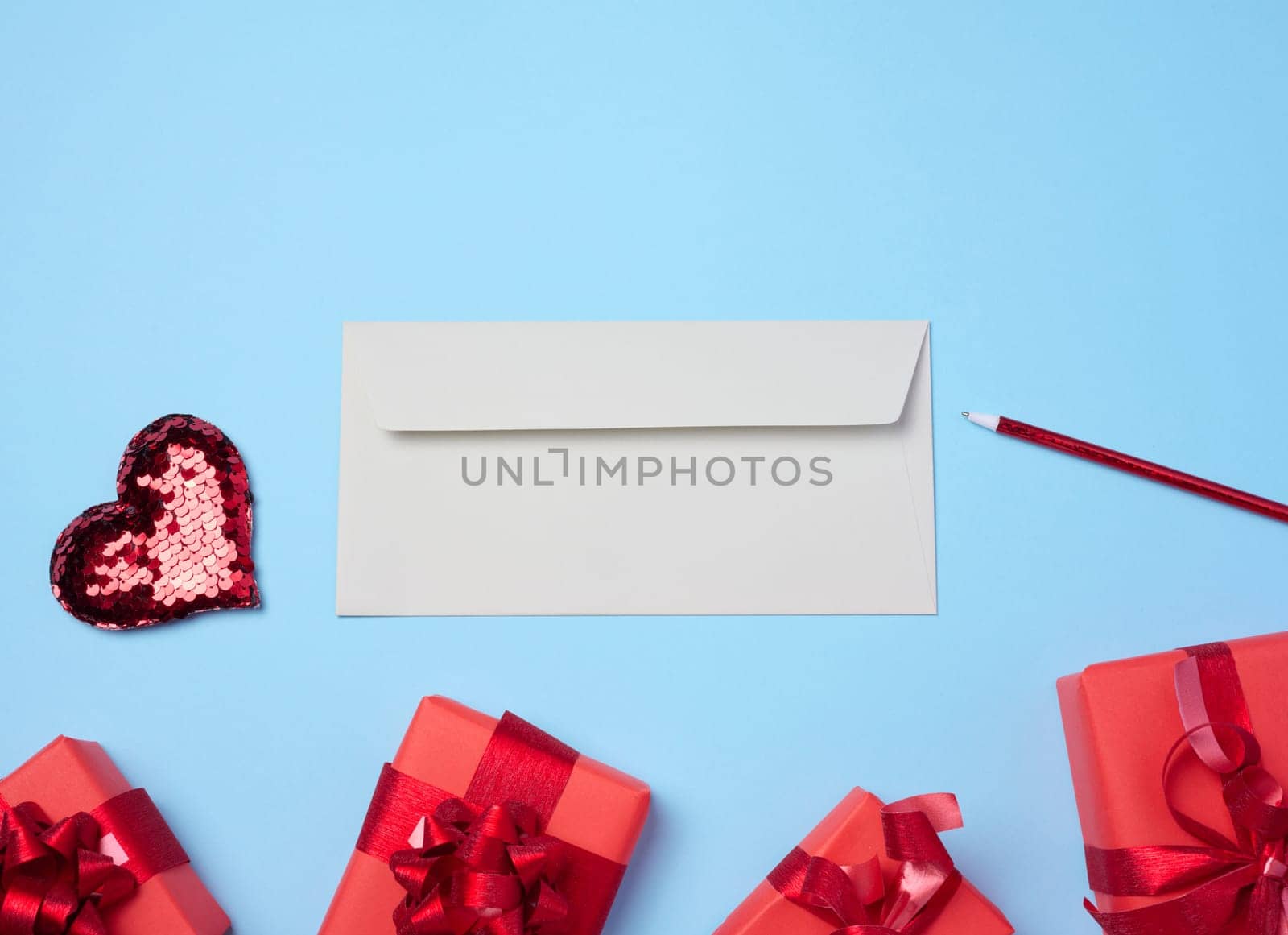 White paper envelope on a blue background, around a box with gifts, top view