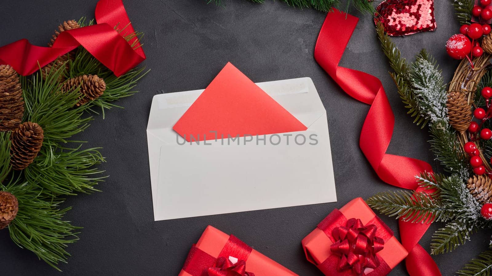 Christmas decor, gifts wrapped in red paper and a letter on a black background, top view