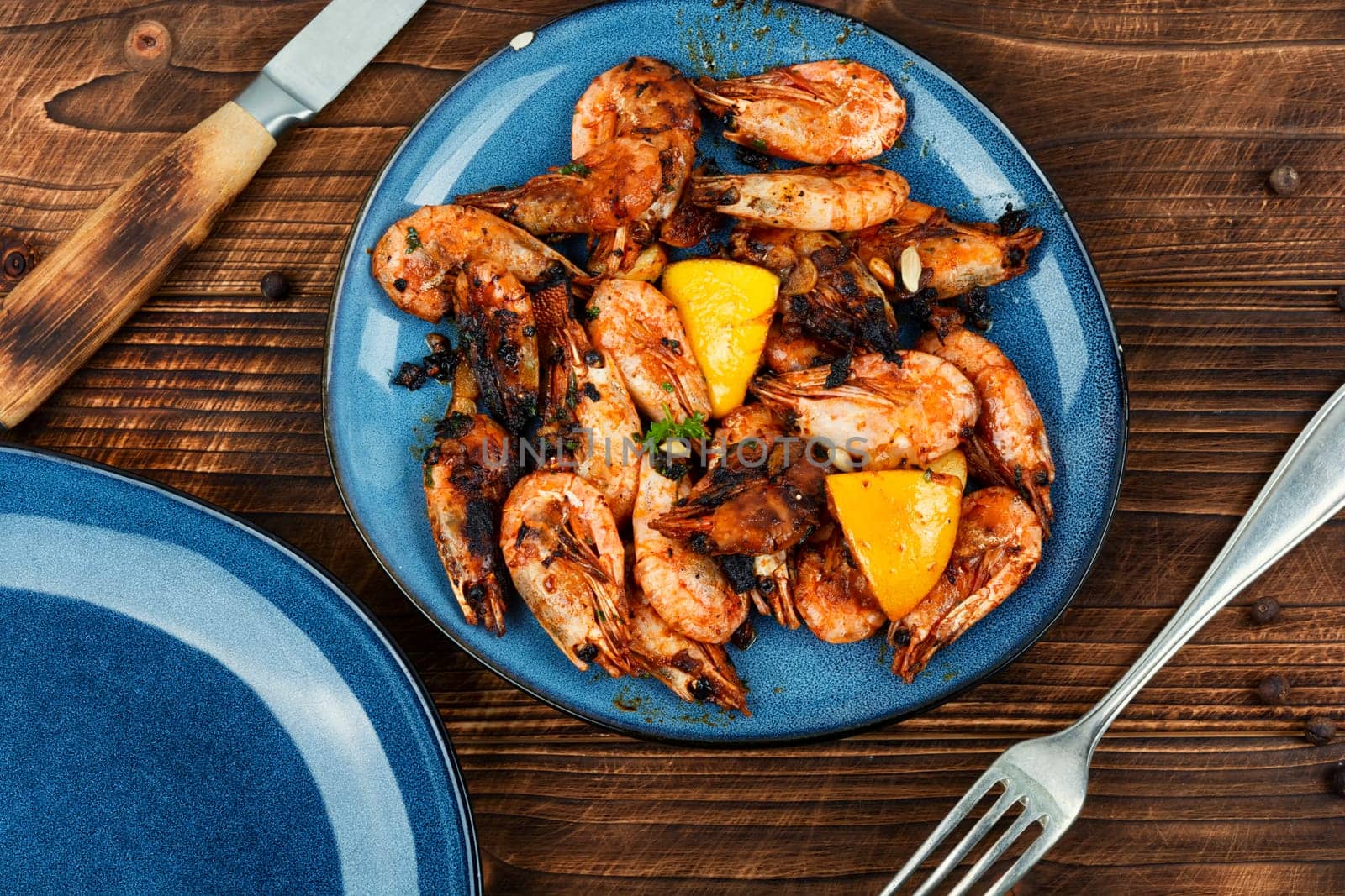 Roasted unpeeled shrimp on a plate. Grilled prawns or shrimps, seafood.