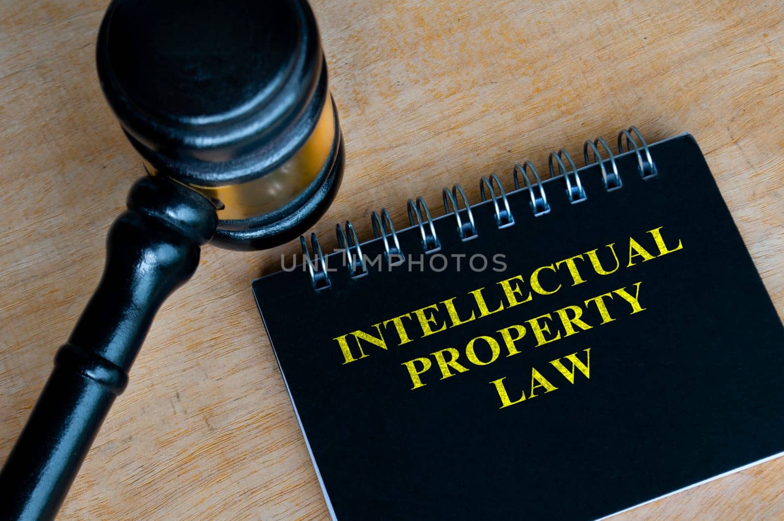 Top view of black notebook with text Intellectual Property Law and with gavel background.