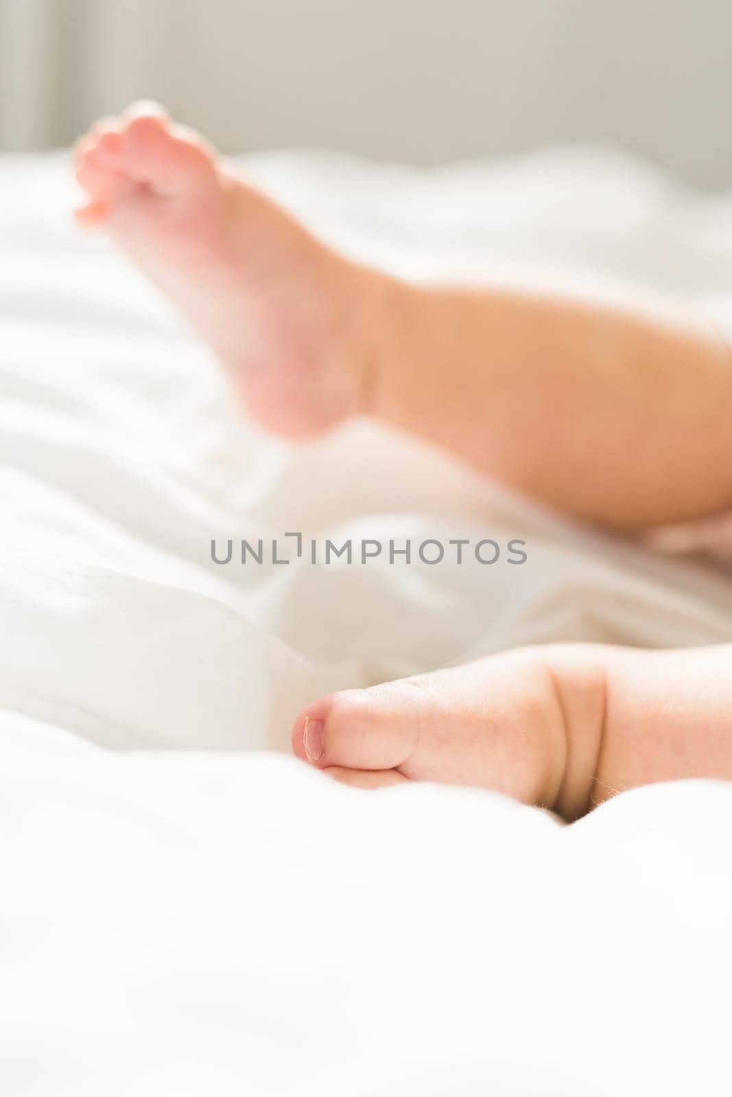 New born baby feet on white blanket on bedroom top view. Child and innocence.
