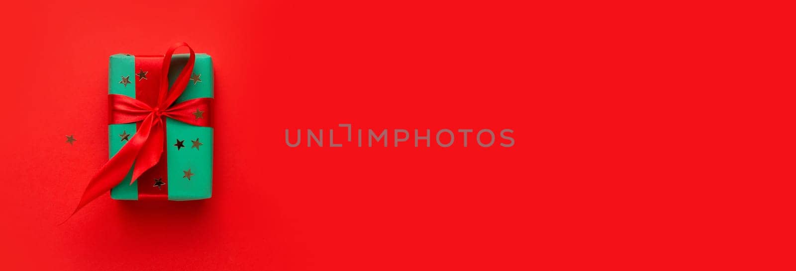 Christmas composition . Christmas gift on the red background . Green box with red ribbon .Flat lay . Top view . Mockup . Copy space .Free space .