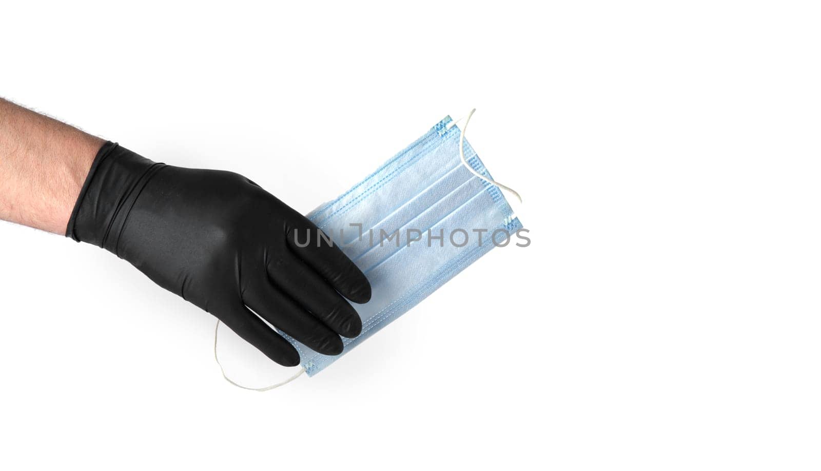 hand in black latex glove holds a disposable medical mask on a white background. selective focus