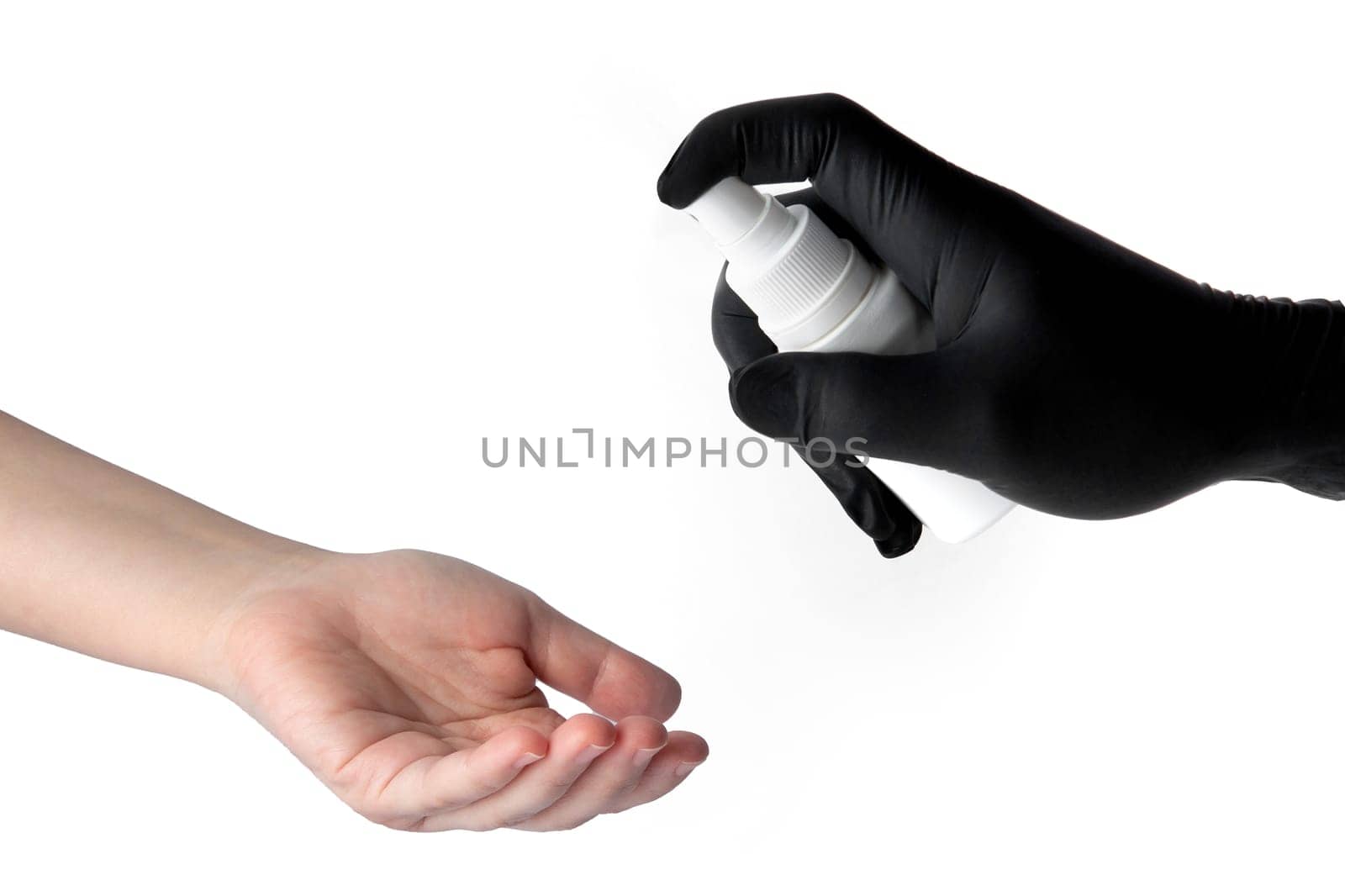 The hand of one person in a black latex glove sprays a disinfectant on the hands of another unprotected person to prevent infection during the Covid-19 epidemic and protect health. High quality photo