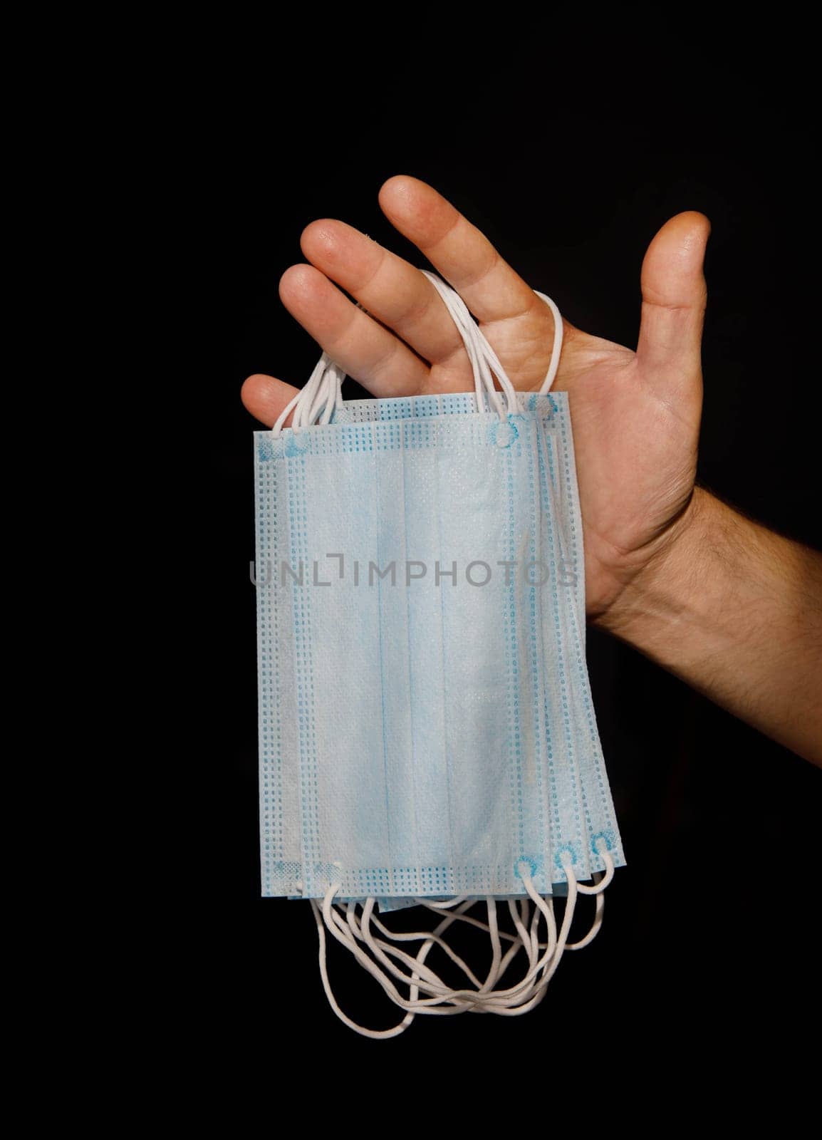 male hand holding several disposable medical masks. selective focus