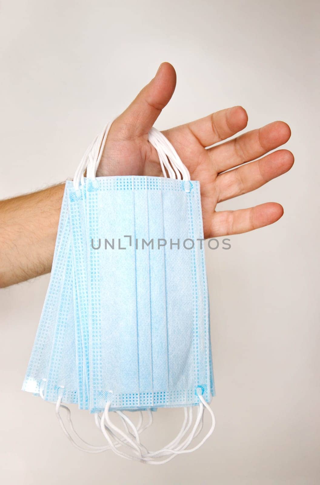 male hand holding several disposable medical masks on the white background . selective focus