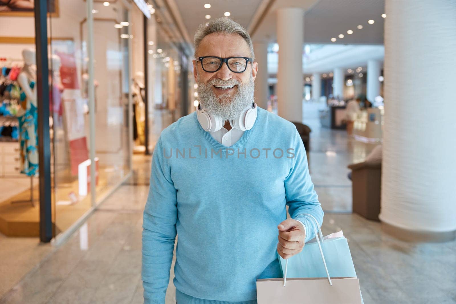 Handsome elegant elderly man with bags in shopping mall. Shopping day concept