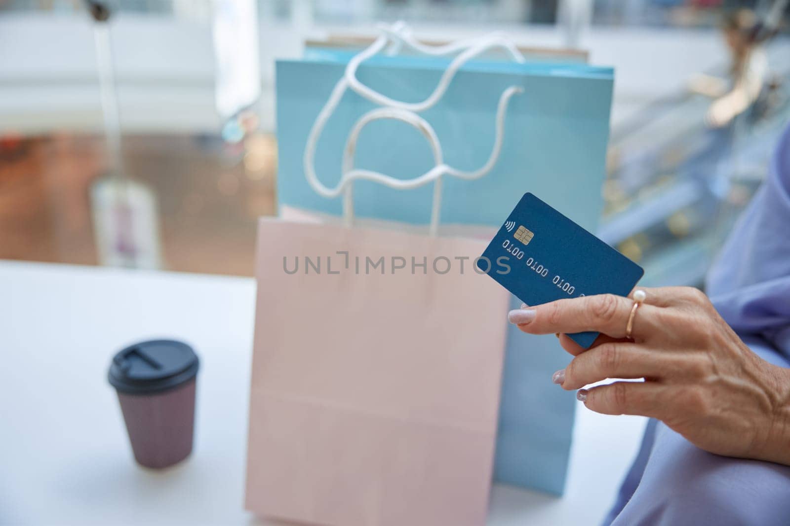 Closeup senior female hand holding credit card for shopping contactless payment. Finance, security and cashback for purchases