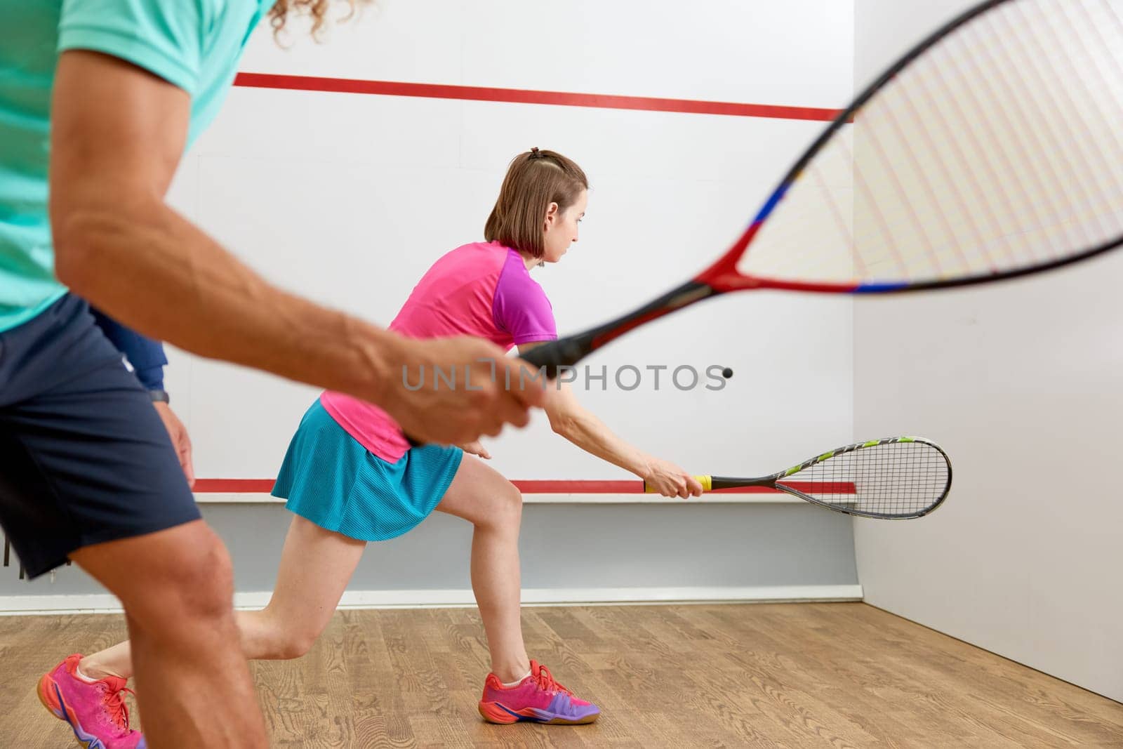 Young people playing squash enjoying recreational pursuit at indoor training club. Couple leisure activity on weekend. Closeup view