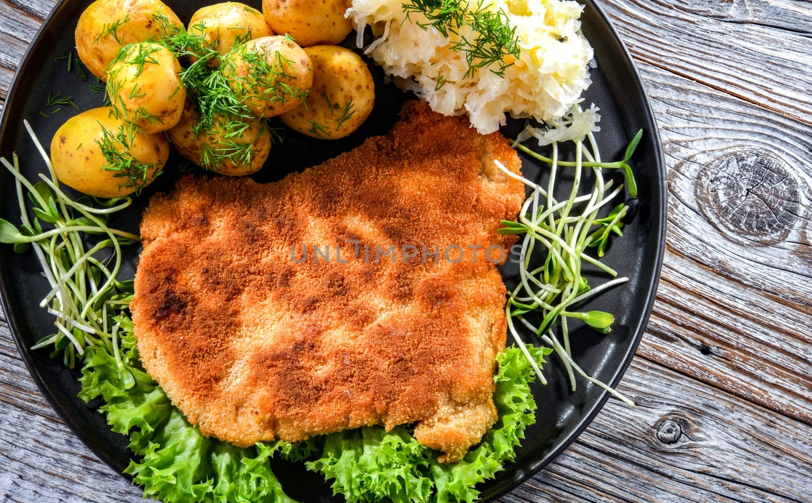 Pork breaded cutlet coated with breadcrumbs served with potatoes and cabbage