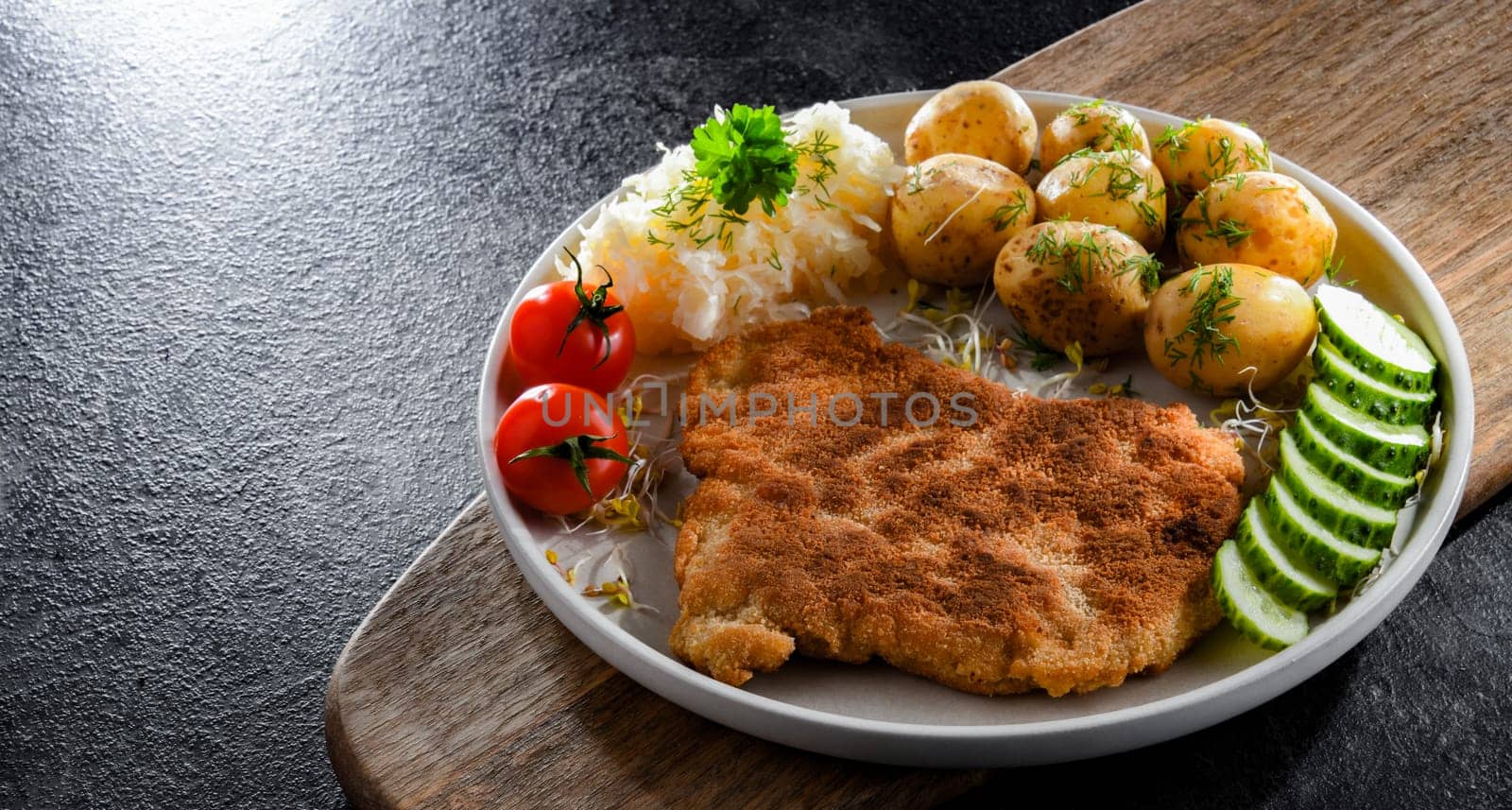 Pork breaded cutlet coated with breadcrumbs served with potatoes and cabbage