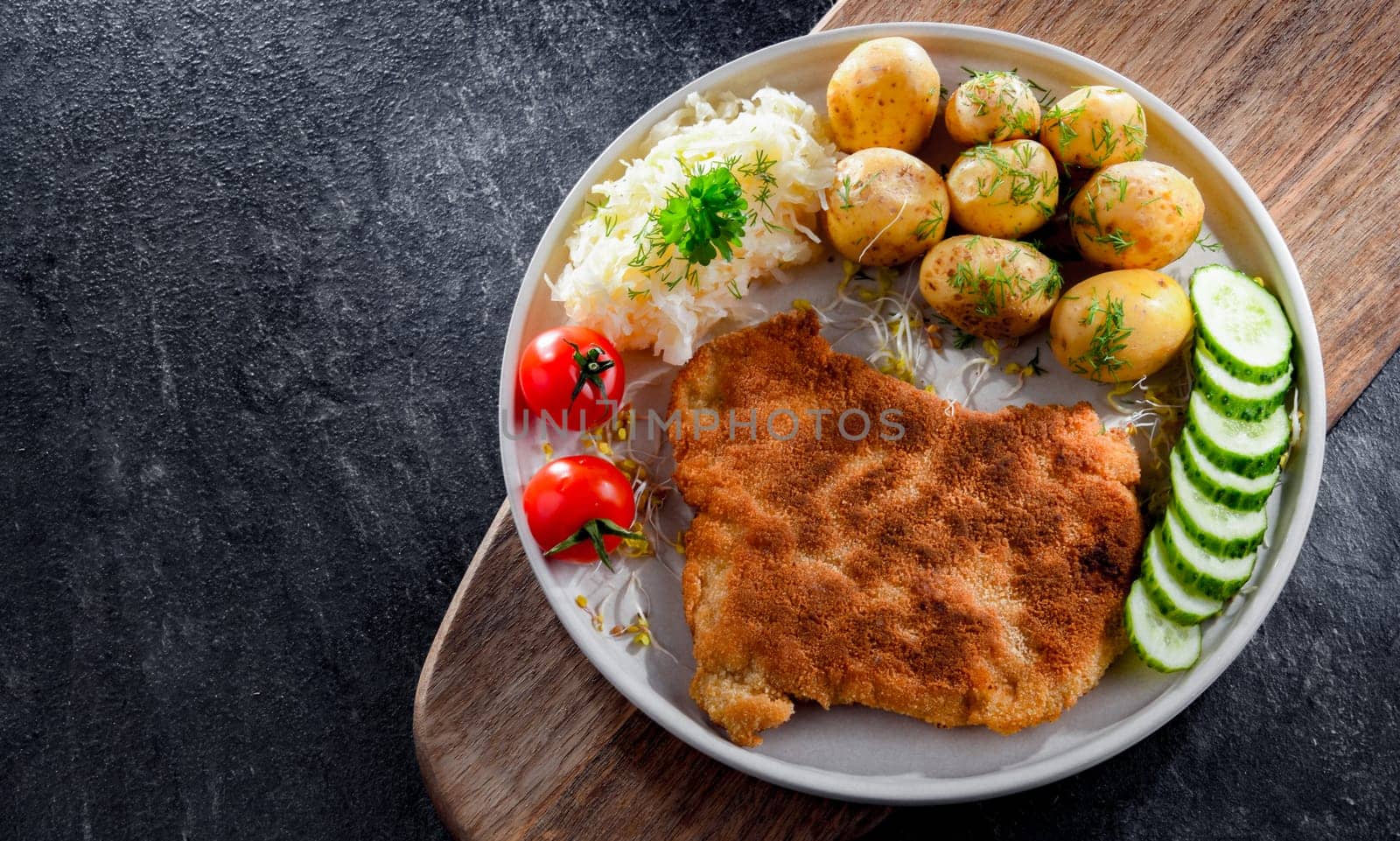 Pork breaded cutlet coated with breadcrumbs served with potatoes and cabbage