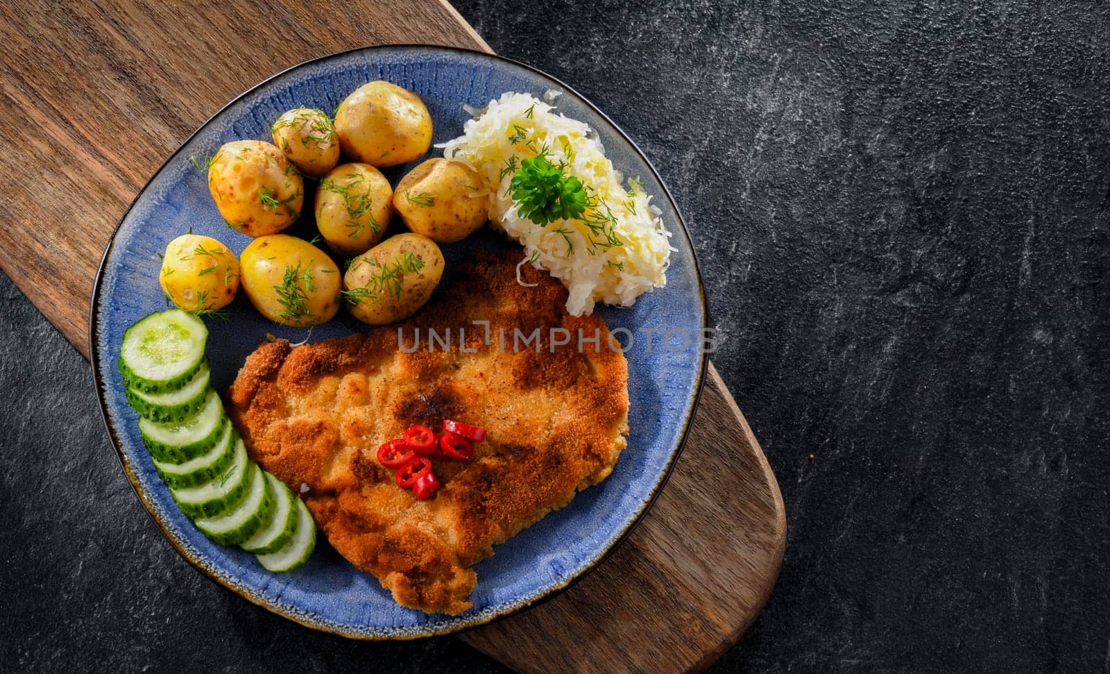 Pork breaded cutlet coated with breadcrumbs served with potatoes and cabbage