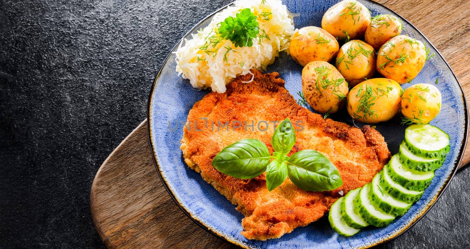 Pork breaded cutlet coated with breadcrumbs served with potatoes and cabbage