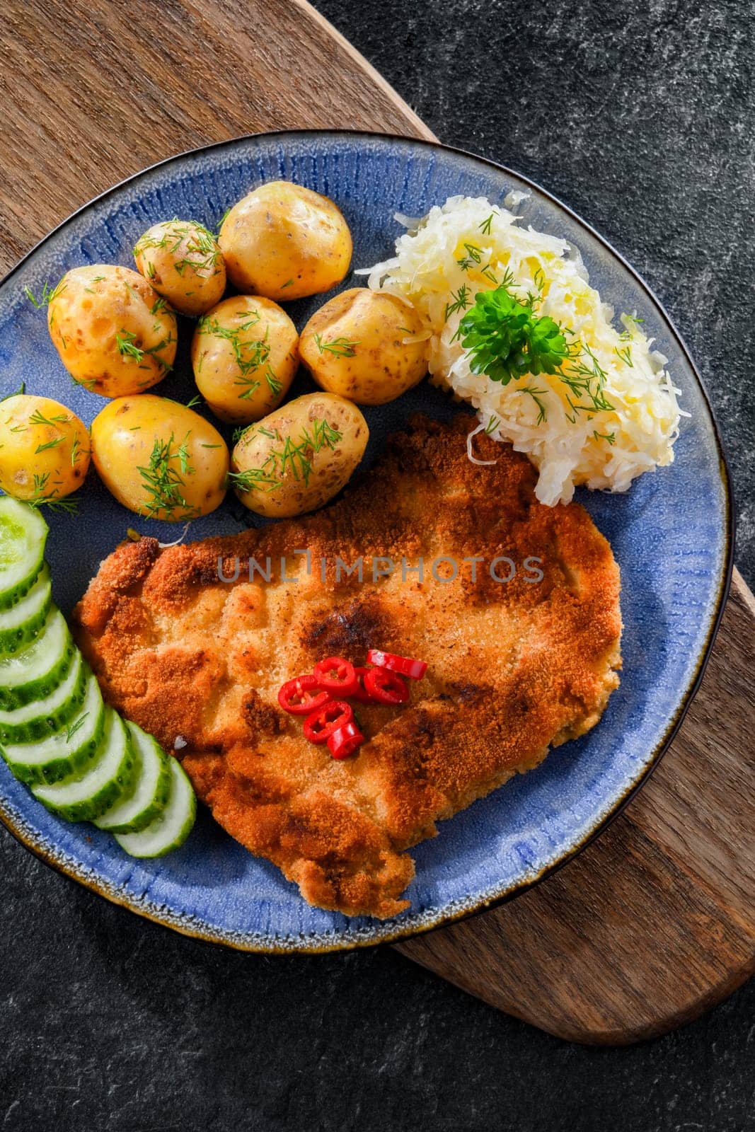 Pork breaded cutlet coated with breadcrumbs served with potatoes and cabbage