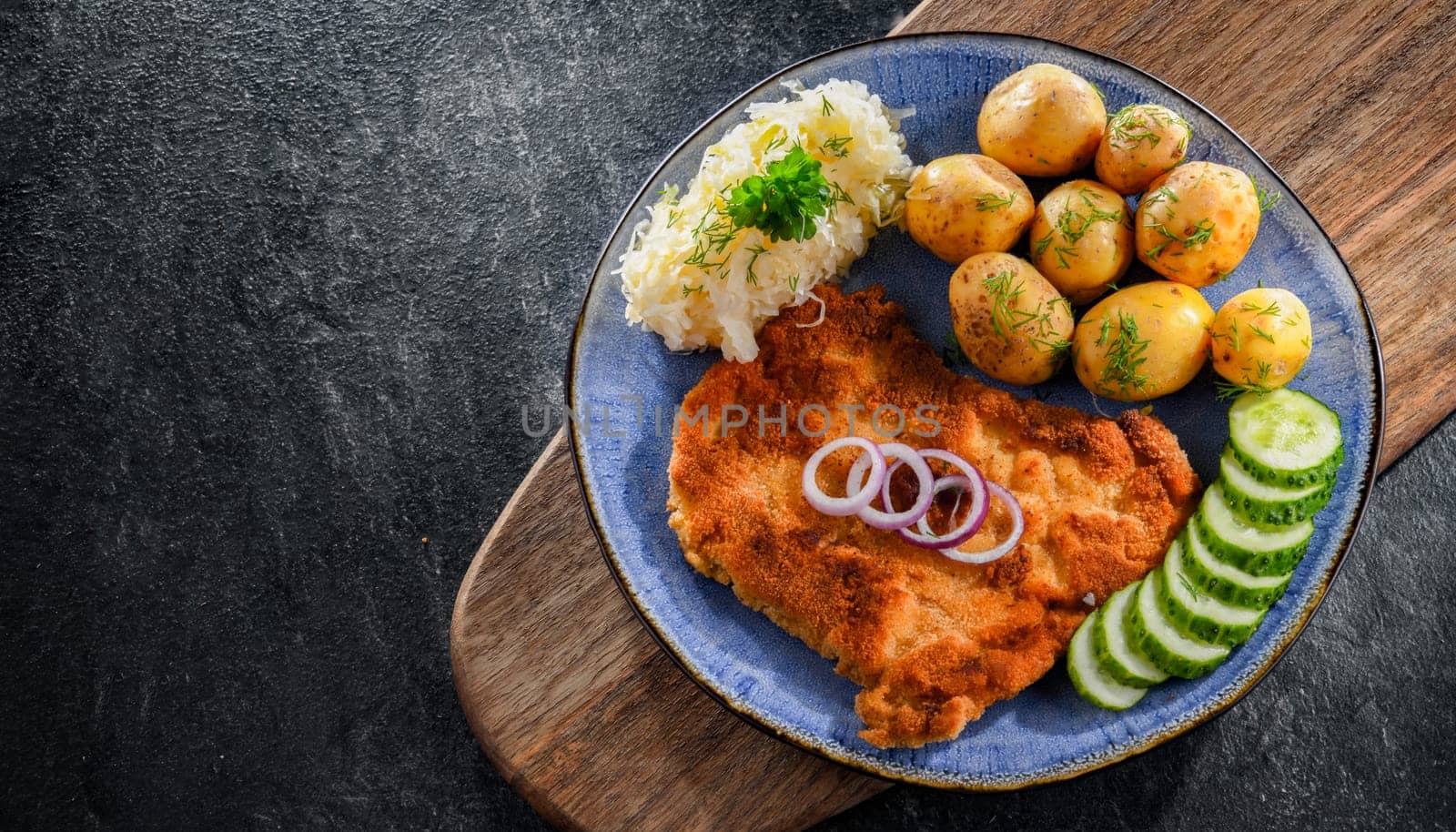 Pork breaded cutlet coated with breadcrumbs served with potatoes and cabbage