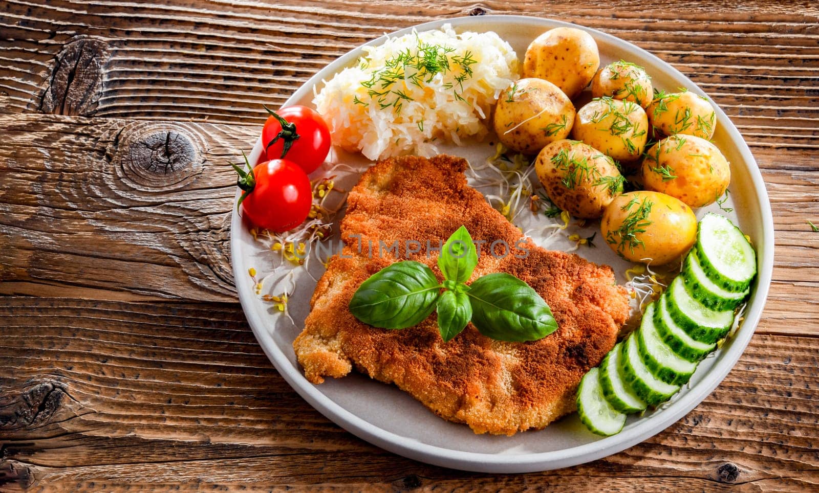 Pork breaded cutlet coated with breadcrumbs served with potatoes and cabbage