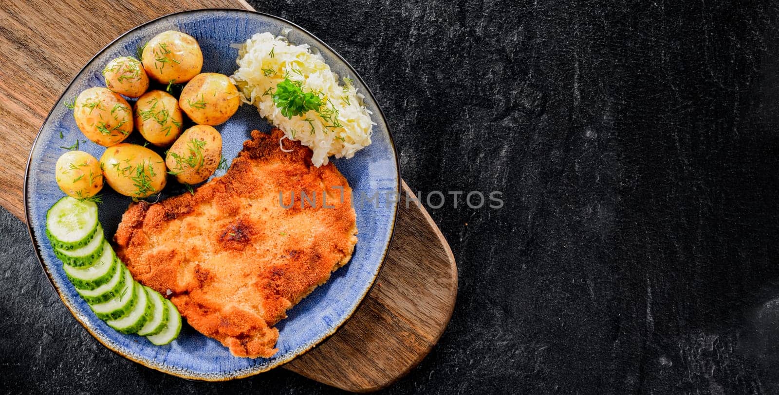 Pork breaded cutlet coated with breadcrumbs served with potatoes and cabbage
