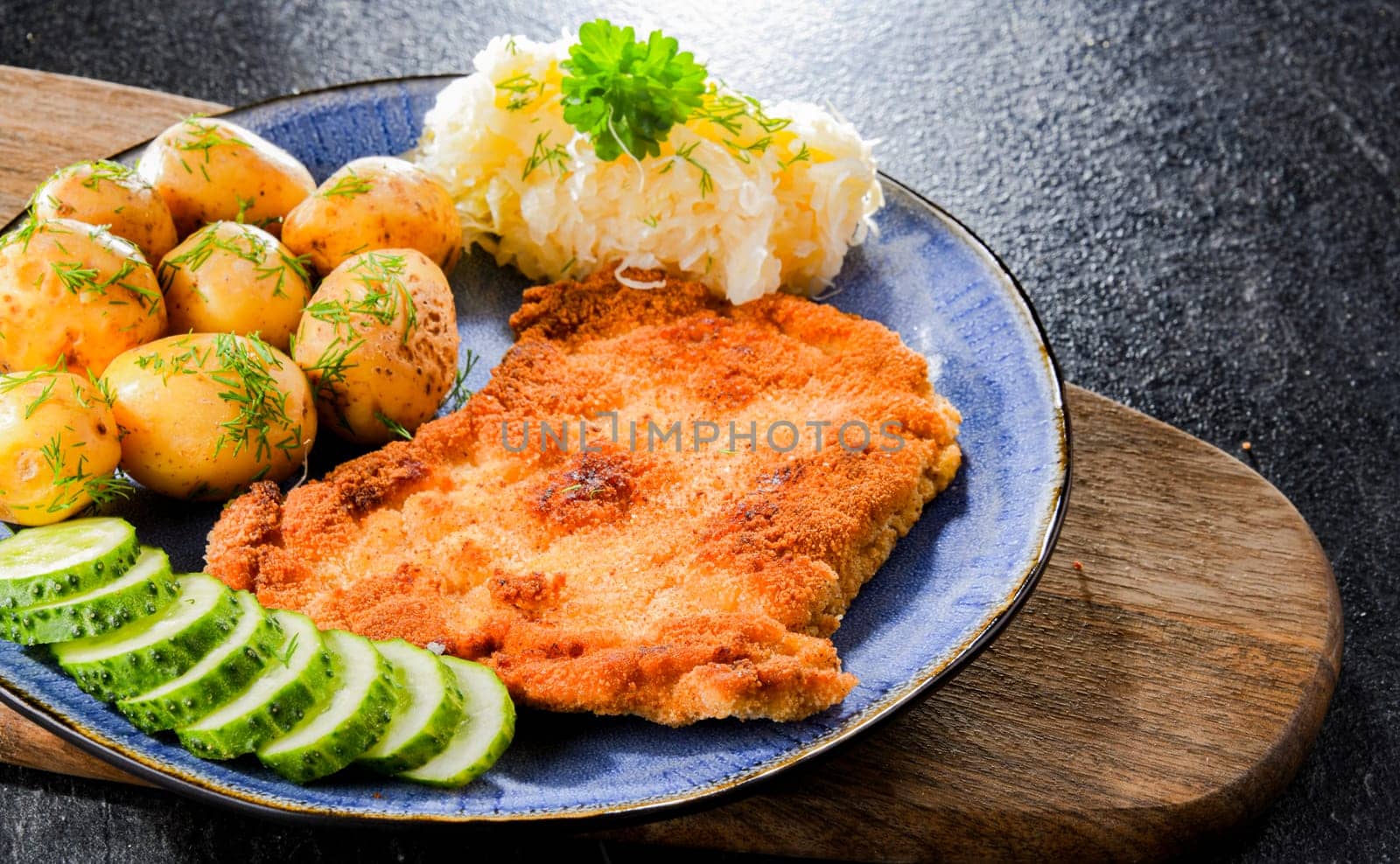 Pork breaded cutlet coated with breadcrumbs served with potatoes and cabbage