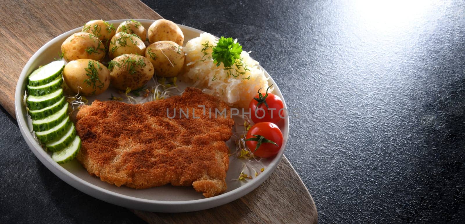 Pork breaded cutlet coated with breadcrumbs served with potatoes and cabbage