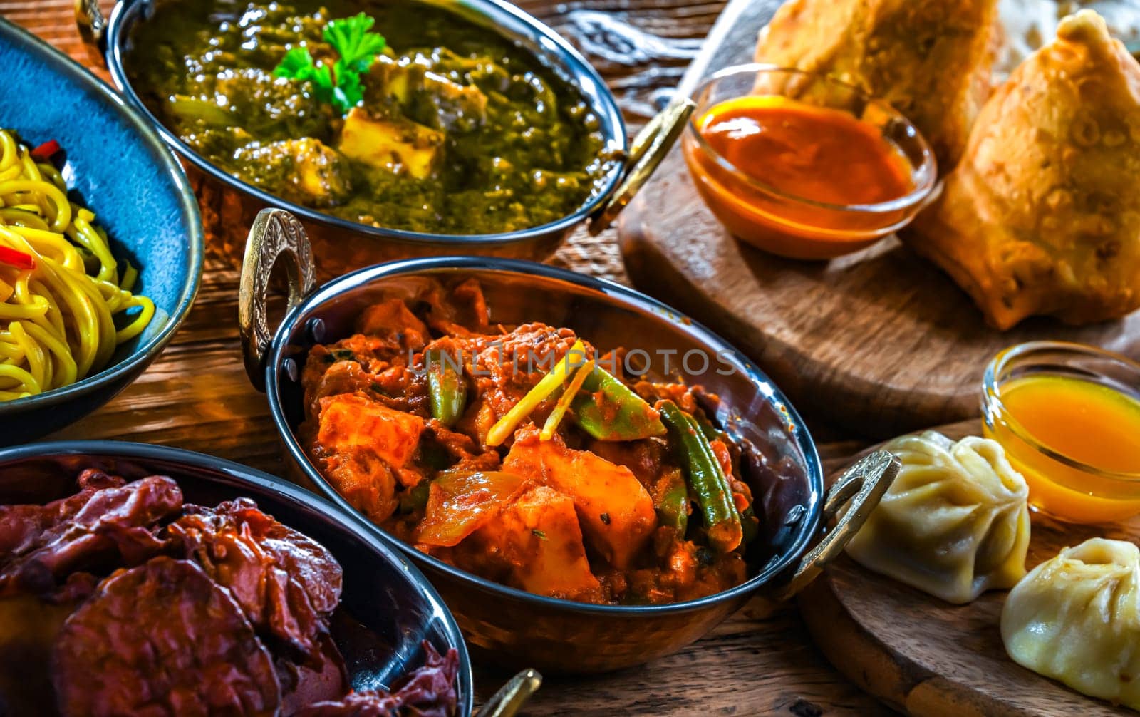 Composition with indian dishes: samosa, pakora, palak paneer, jalfrezi, thukpa and naan bread
