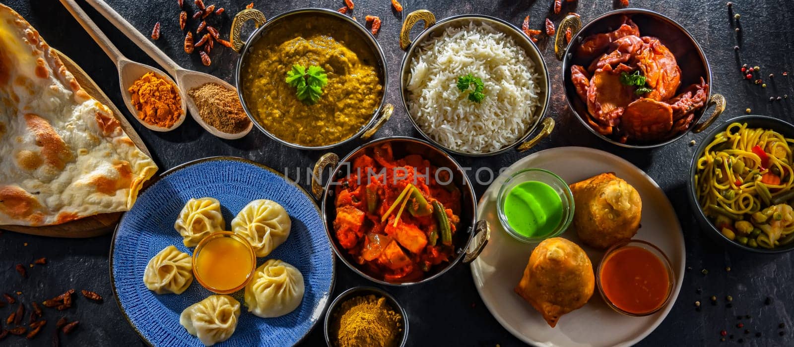 Composition with indian dishes: samosa, pakora, palak paneer, jalfrezi, thukpa and naan bread
