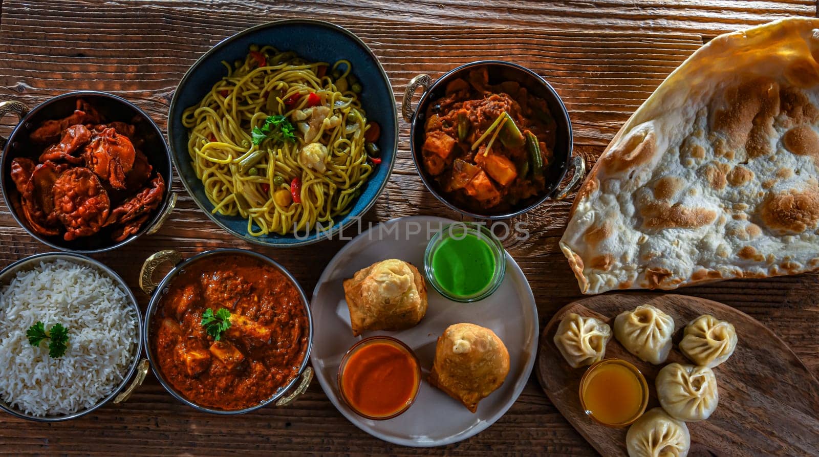 Composition with indian dishes: samosa, pakora, palak paneer, jalfrezi, thukpa and naan bread
