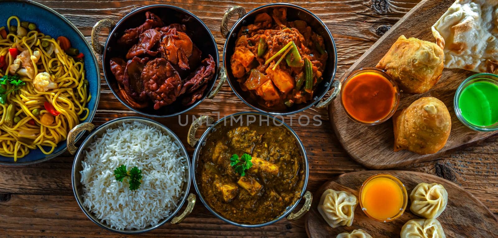 Composition with indian dishes: samosa, pakora, palak paneer, jalfrezi, thukpa and naan bread