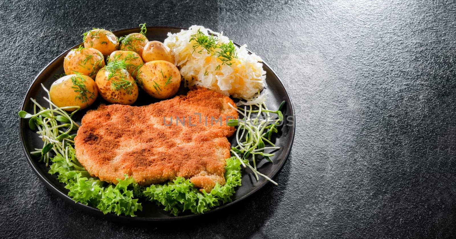 Pork breaded cutlet coated with breadcrumbs served with potatoes and cabbage