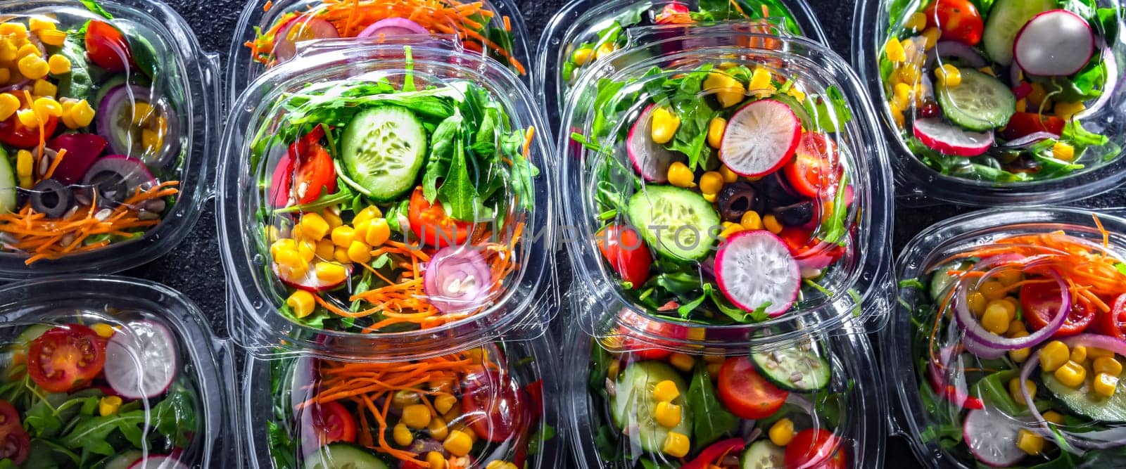 Plastic boxes with pre-packaged vegetable salads, put up for sale in a commercial refrigerator